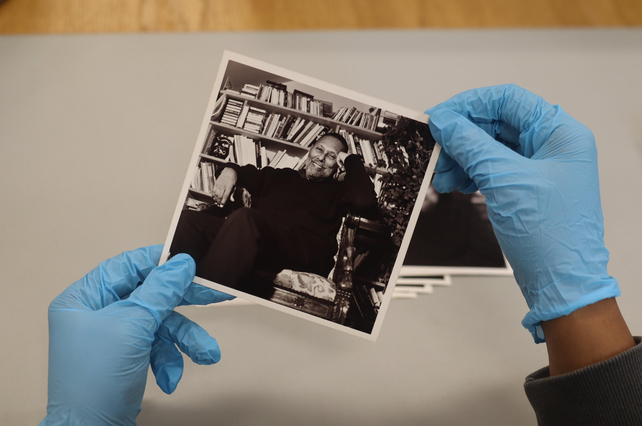 a person wearing blue gloves holds an archived photographs of theorist Stuart Hall